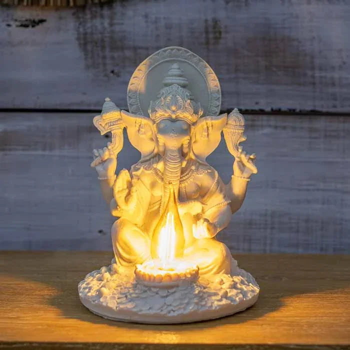 Luminária de Ganesha em marmorite branco com lâmpada de filamento acesa, destacando os detalhes da escultura.