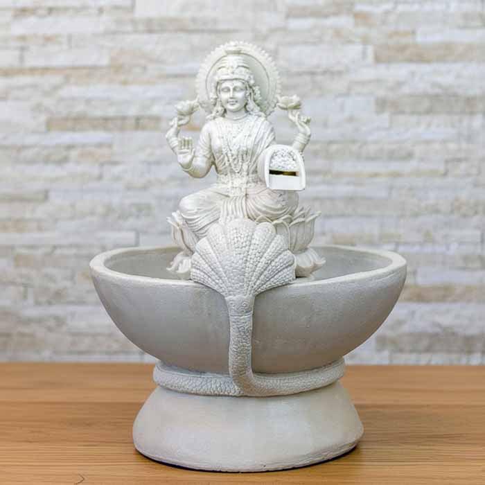 Fonte de água em marmorite da Deusa Lakshmi com iluminação LED destacando o fluxo da água sobre a base de lótus.