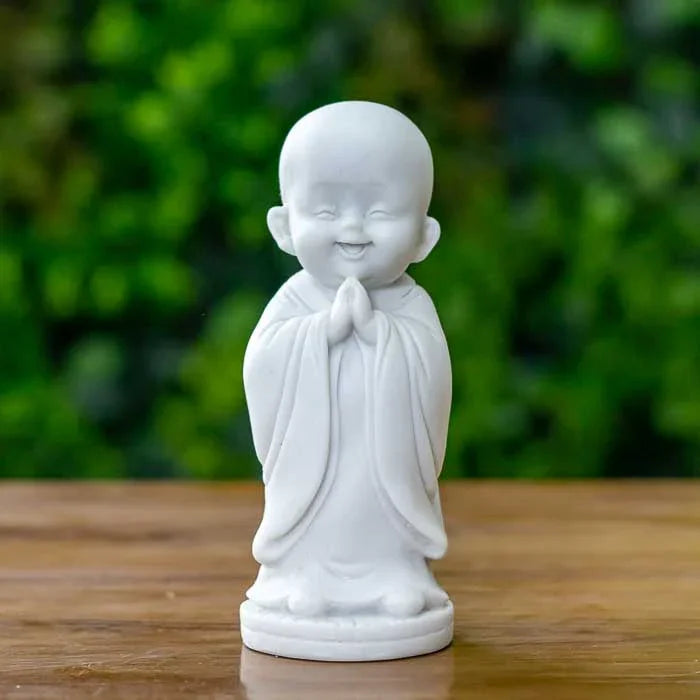 Escultura de monge sorridente em pé com mãos unidas em oração