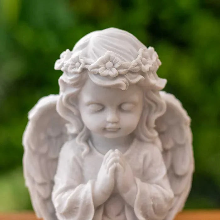 Anjo de marmorite com mãos juntas e expressão serena sobre base com LED