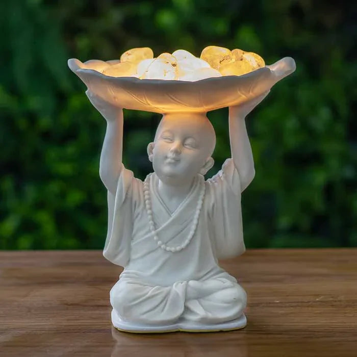 Escultura de monge em marmorite com pedras iluminadas sobre a cabeça