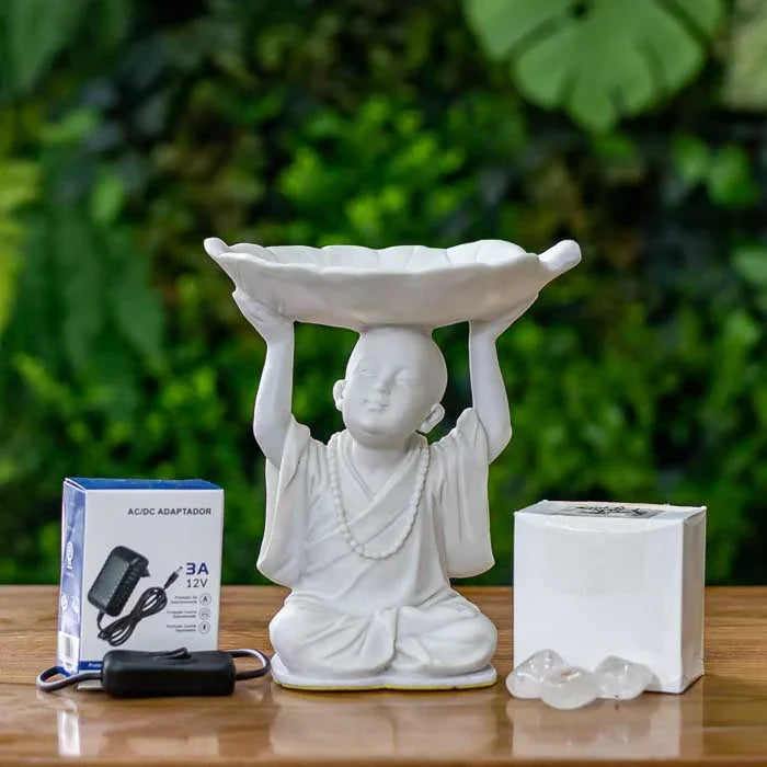 Escultura clara com monge segurando folha com pedras luminosas