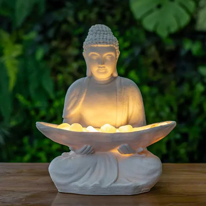 Escultura de Buda com pedras iluminadas sobre as pernas