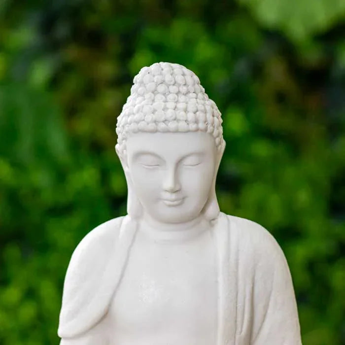Buda branco sentado com base de luz suave e pedras decorativas