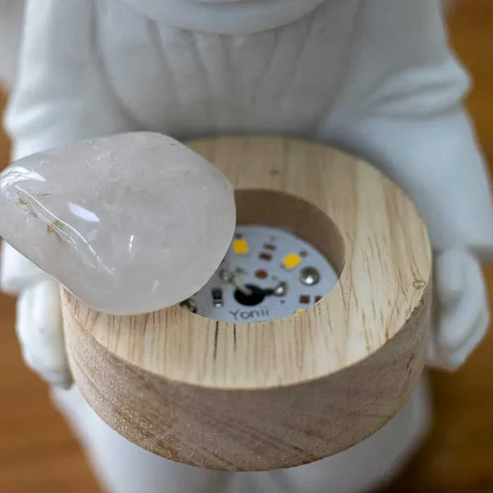 Objeto religioso delicado com criança anjo segurando uma pedra
