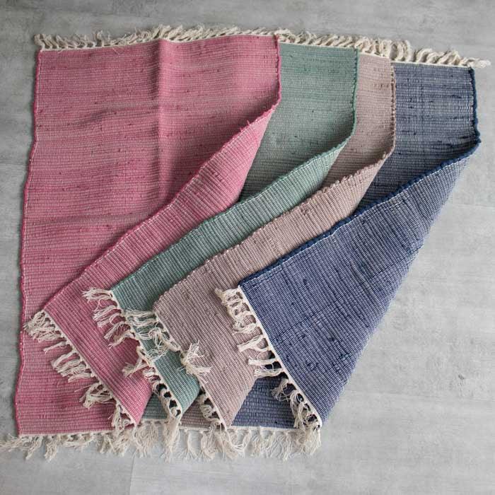 Tapete artesanal produzido no Brasil, feito à mão com tramas naturais e acabamento afetivo em tons suaves.