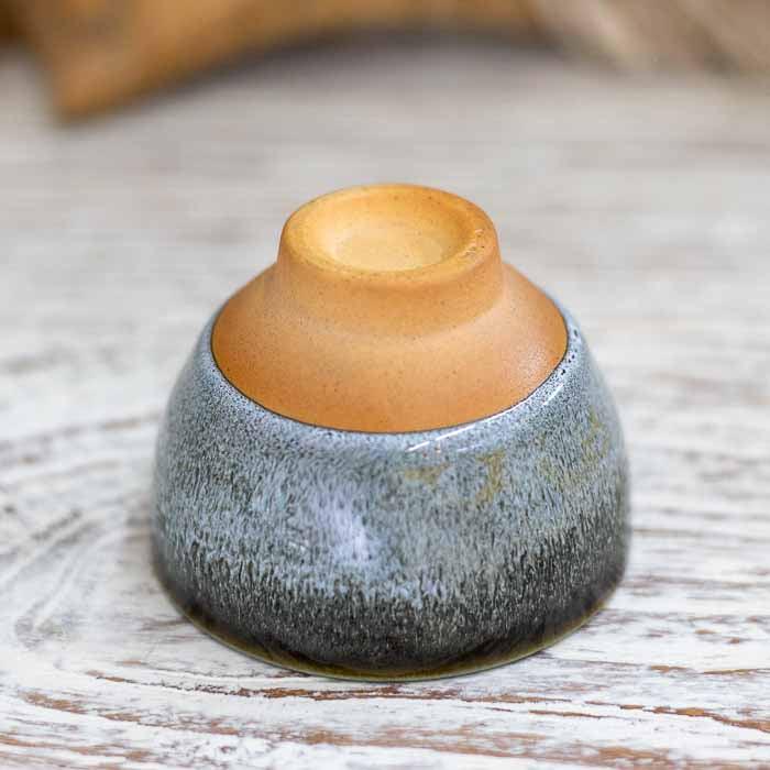 Pequeno bowl de cerâmica indiana para rituais de chá sobre mesa de madeira branca.