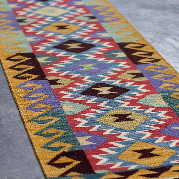 Tapete Kilim afegão de trama plana decorando corredor com paredes claras.