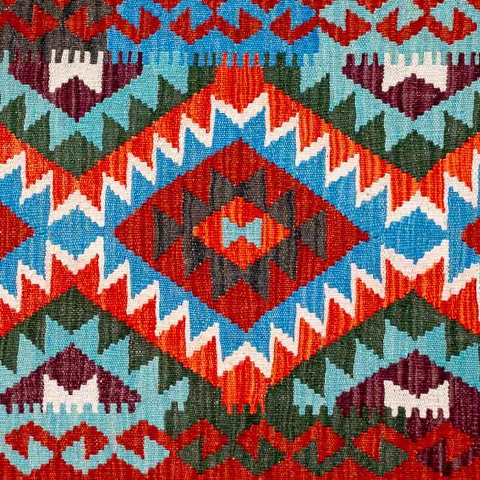 Passadeira artesanal Kilim do Afeganistão apresentando grafismos étnicos multicoloridos sobre trama manual plana de lã.