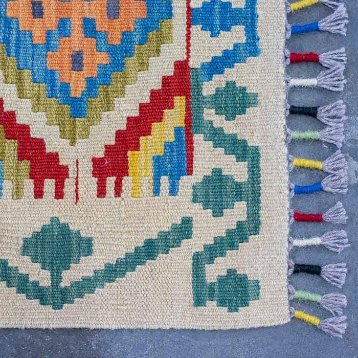 Peça têxtil exclusiva tecida manualmente no Afeganistão com simbologia ancestral multicolorida.