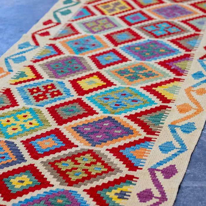 Detalhe da trama plana artesanal de passadeira Kilim em fibras naturais de lã e algodão.