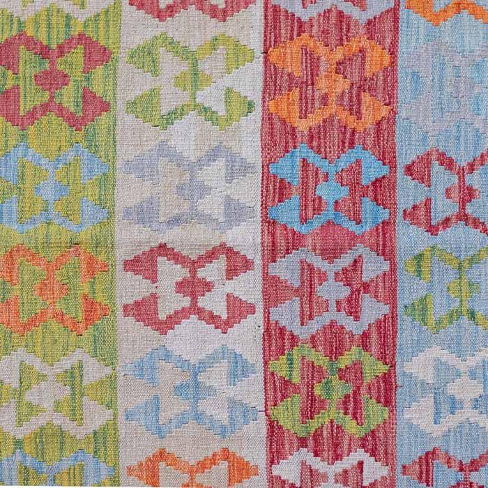 Tapete colorido artesanal kilim do Afeganistão com padrões geométricos tribais sobre piso cinza.