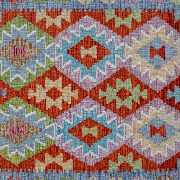Tapete artesanal Kilim do Afeganistão com grafismos étnicos simétricos sobre trama manual plana de lã natural.