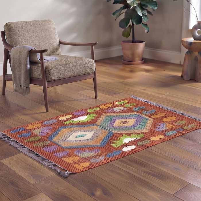 Tapete pequeno estilo étnico com desenhos de losangos e franjas coloridas.