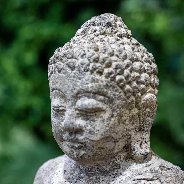 Escultura espiritual para jardim com expressão serena e acabamento rústico.