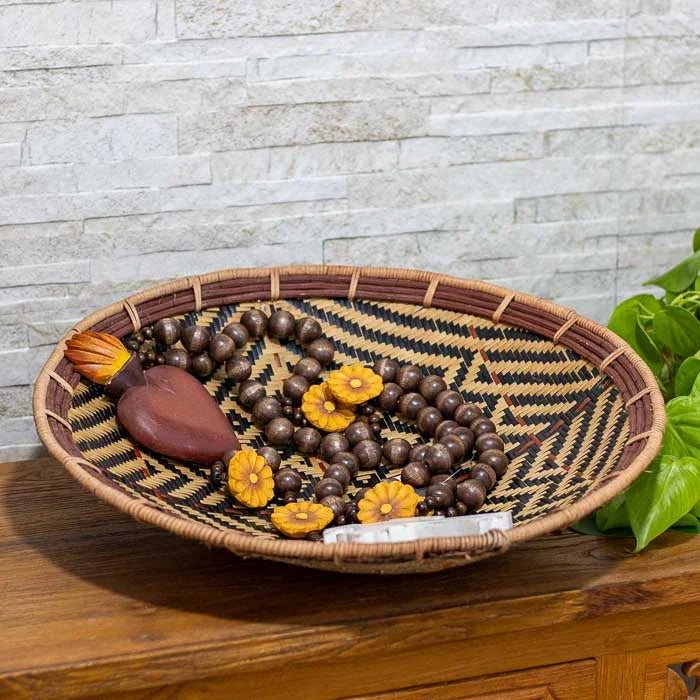 Cesto decorativo com borda vermelha e técnica ancestral de trançado.