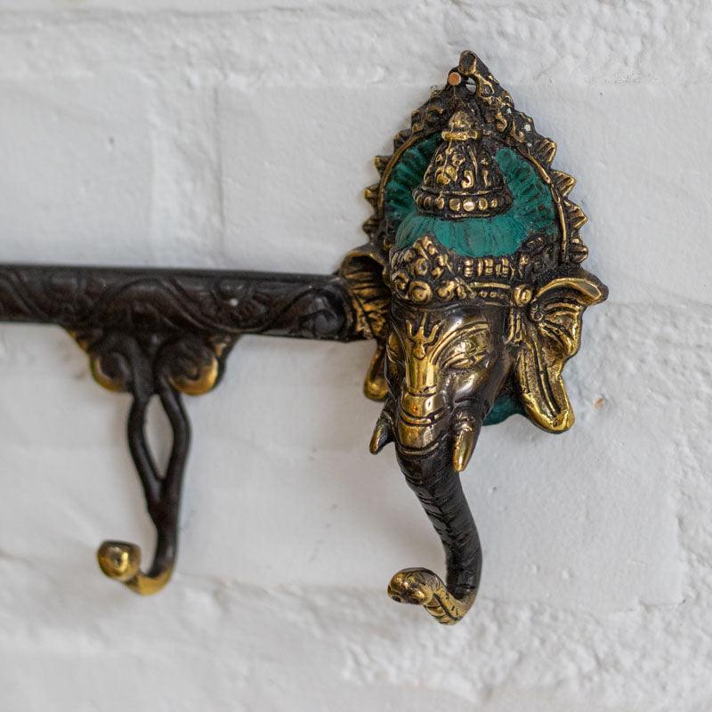 Cabideiro de parede artesanal em bronze dourado de Bali com duas cabeças de Ganesh e pátina verde.