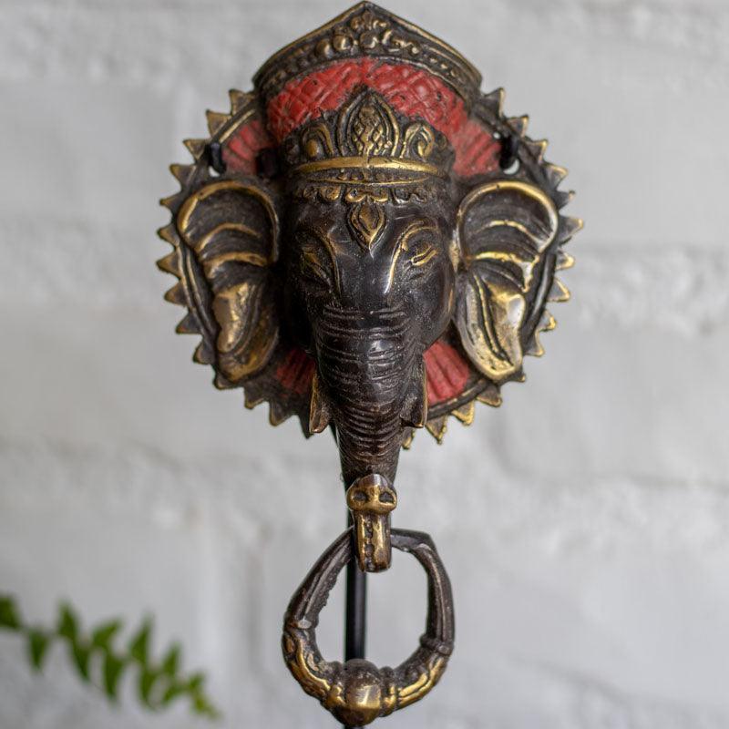 Obra hindu Ganesh Face em bronze com detalhes dourado e vermelho.