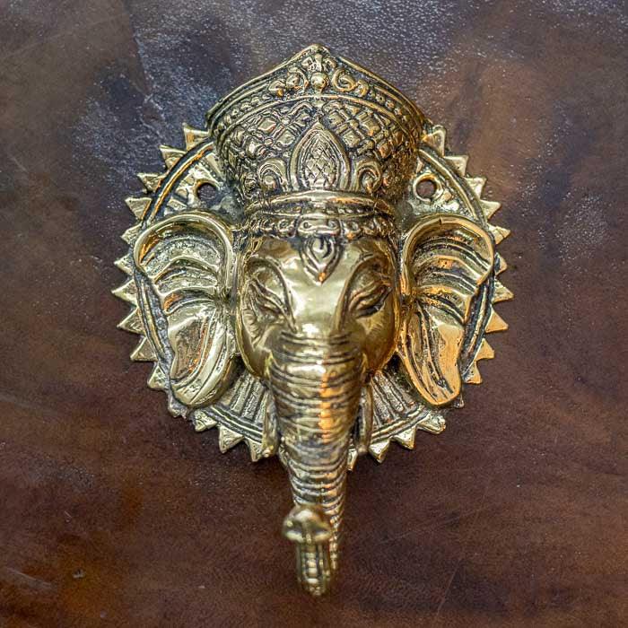 Escultura funcional em bronze representando o deus Ganesha, utilizada como puxador de porta artesanal, com acabamento preto e verde em estilo balinês tradicional.