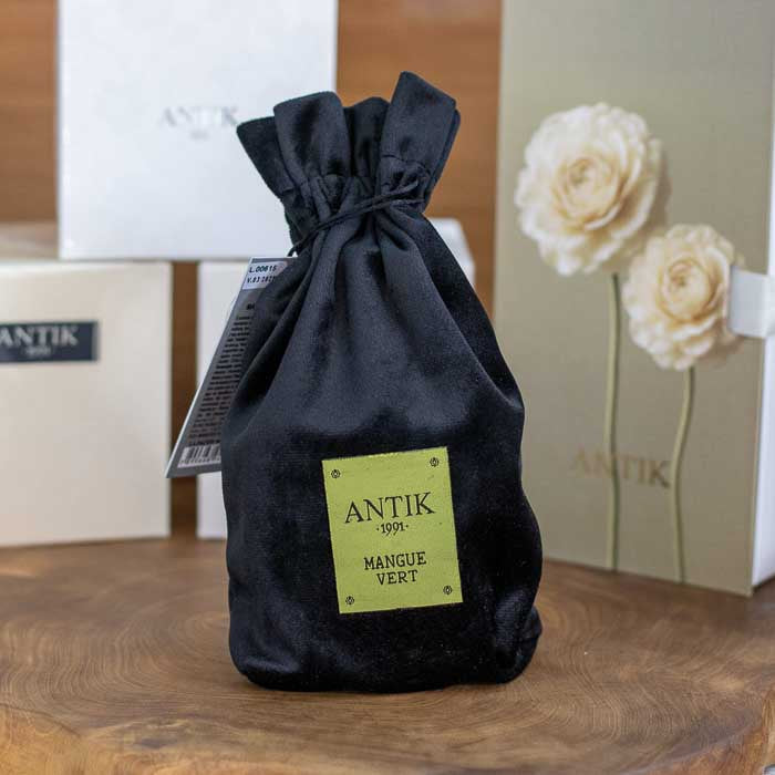 Embalagem de presente em veludo preto com etiqueta verde limão da fragrância Mangue Vert Antik.