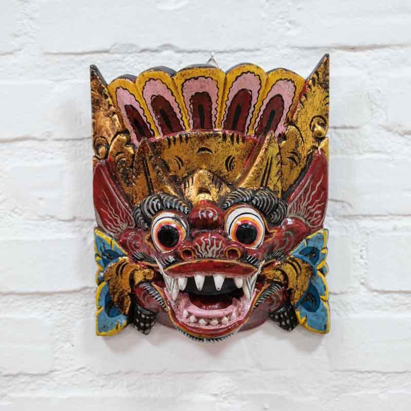 Máscara frontal de Barong entalhada em madeira com dentes de javali e coroa ornamental em estilo balinês.