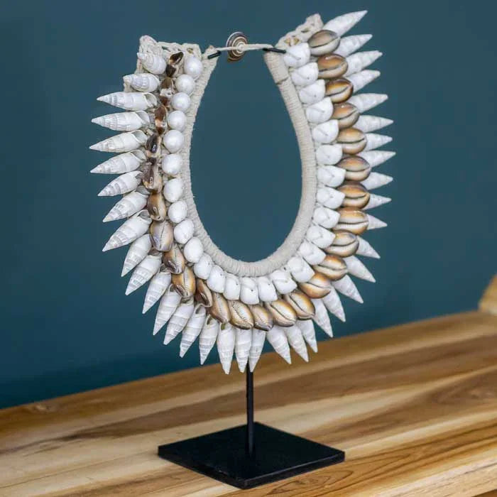 Escultura de colar tribal com conchas, perfeita para ambientes tropicais.