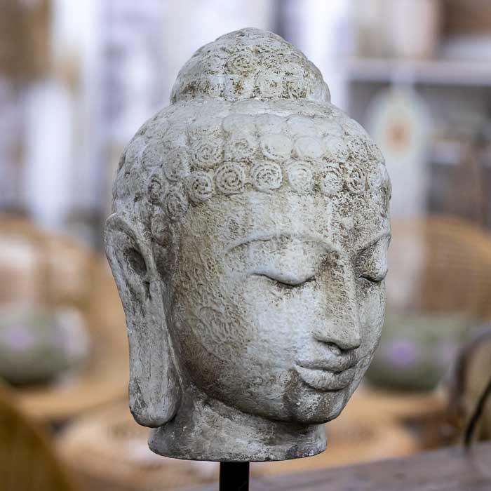 Cabeça de Buda artesanal em cimento com textura marcada e base de ferro, ideal para composições contemplativas e ambientes espirituais.