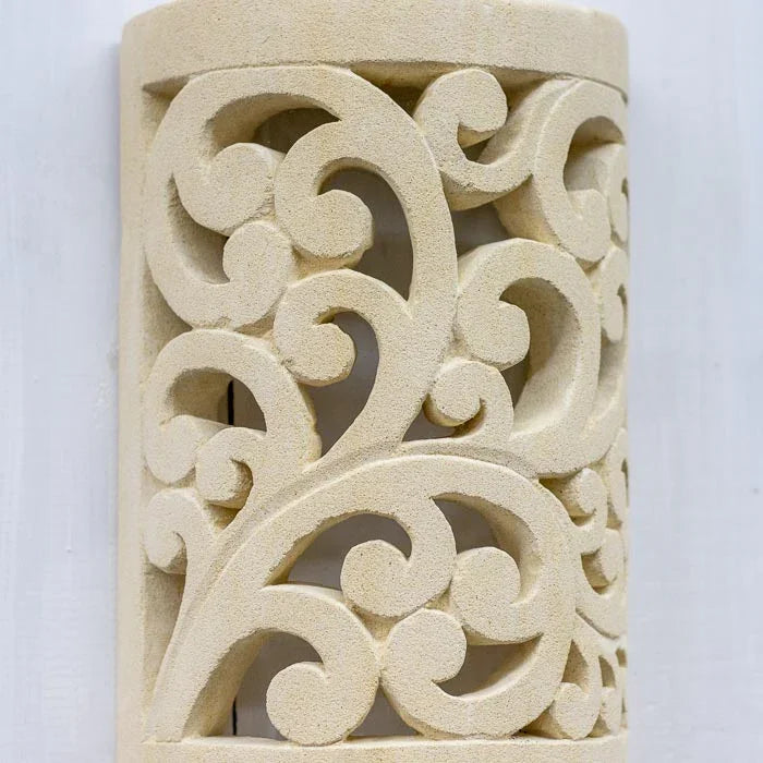 Detalhe do entalhe profundo da arandela em limestone, evidenciando o trabalho manual.