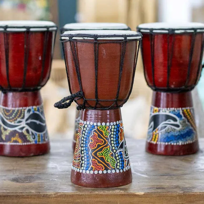 Tambor artesanal de pequeno porte com acabamento natural e referências visuais à estética aborígene tradicional