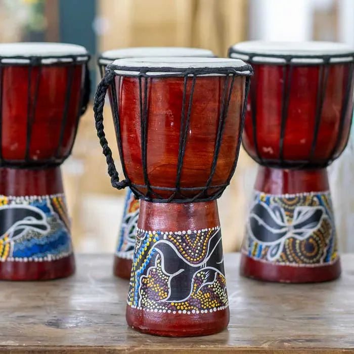 Djembê decorativo com formas arredondadas, base de madeira e pintura étnica representando heranças culturais