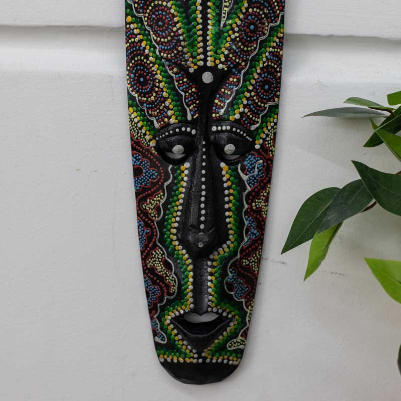 Máscara artesanal de Bali com acabamento em tons vivos e simbolismo protetor.