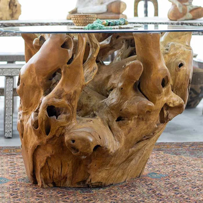 Mesa de madeira teca com base de raiz inteira e tampo de vidro transparente criada artesanalmente em Bali para compor salas de jantar com personalidade.