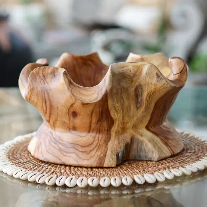 Centro de mesa em teca maciça produzido manualmente em Bali, exibindo ondulações naturais e tom médio perfeito para compor ambientes elegantes.