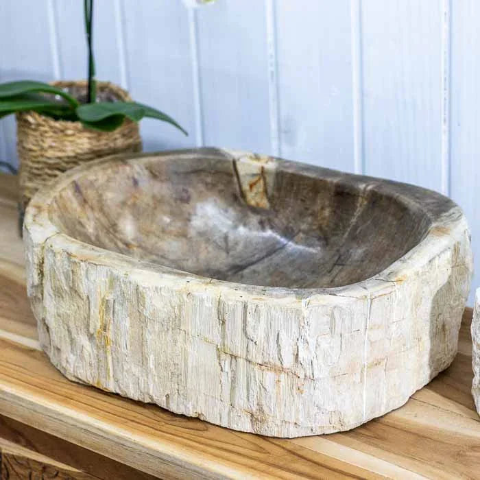 Cuba de pia artesanal em madeira petrificada, com exterior rústico e forma orgânica.