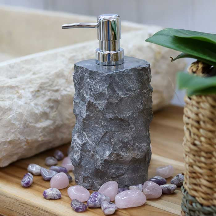 Saboneteira de pedra rústica escura com válvula cromada, peça artesanal de Bali perfeita para banheiros com estética natural.