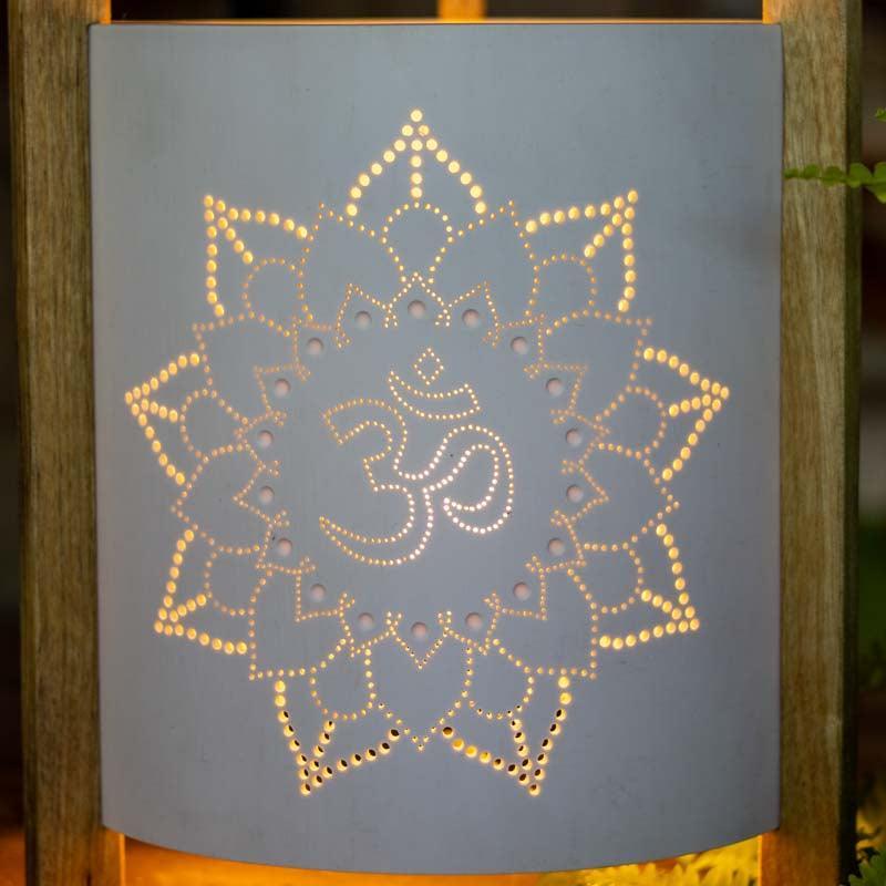 Detalhe da luz projetada através dos furos manuais de uma mandala de lótus em luminária artesanal.
