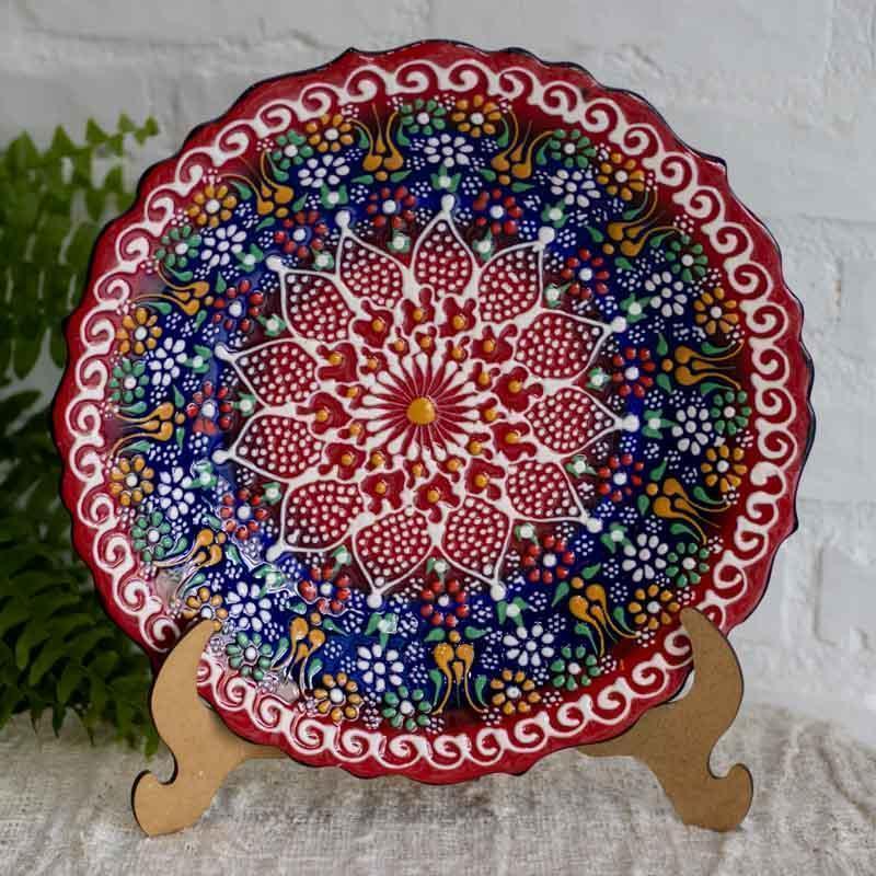 Detalhe central de flor em relevo em prato de 30cm, mostrando a profundidade das camadas de tinta e esmalte.