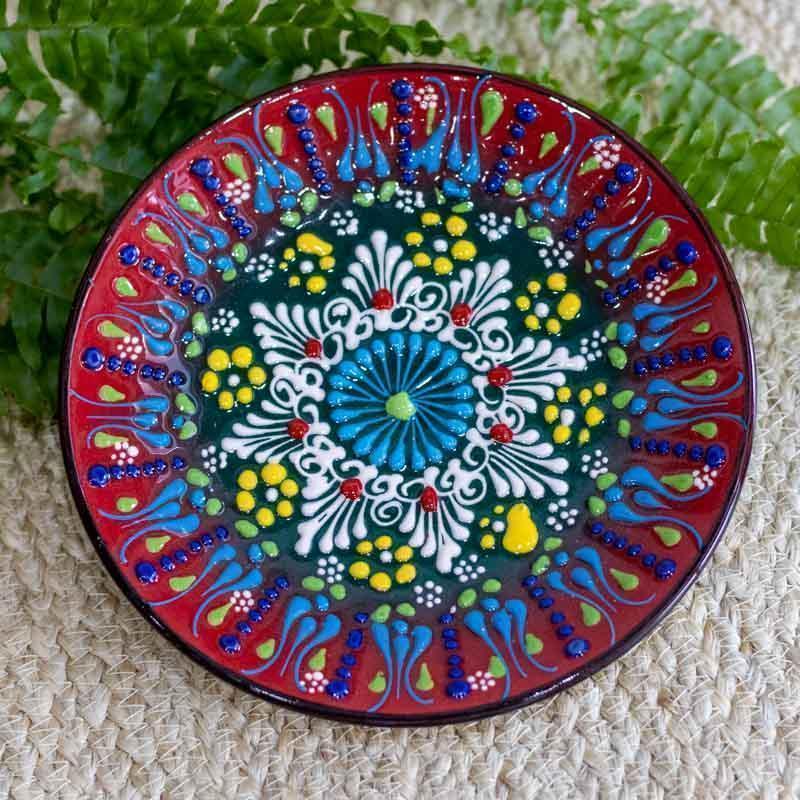 Detalhe central de prato artesanal com mandala colorida em relevo, evidenciando a maestria da pintura manual turca.