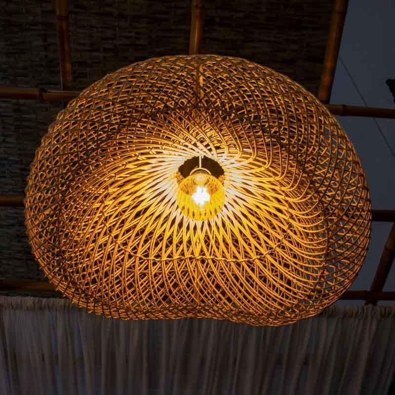 Iluminação zen com luminária de fibra natural integrada a ambiente com plantas e móveis de madeira.