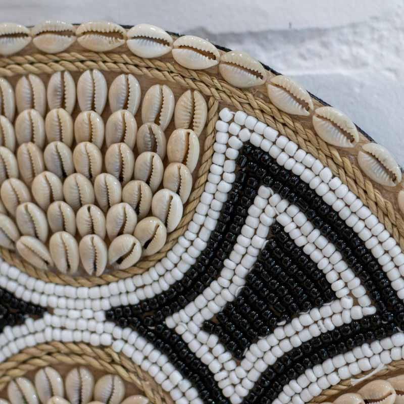 Decoração de parede inspirada em Bali com mandala de búzios naturais e acabamento em miçangas.