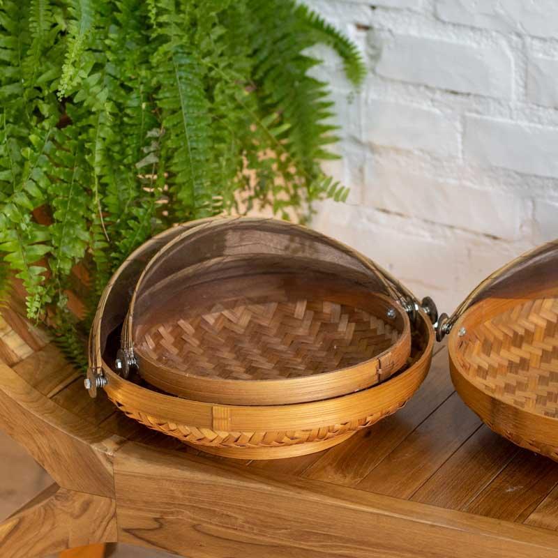 Cesta média (M) de Bali com tela fechada protegendo frutas frescas sobre uma mesa de madeira em área externa.