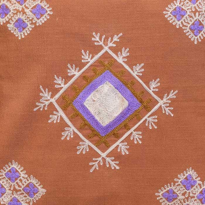 Almofada artesanal com tassels brancos em cada um dos quatro cantos.