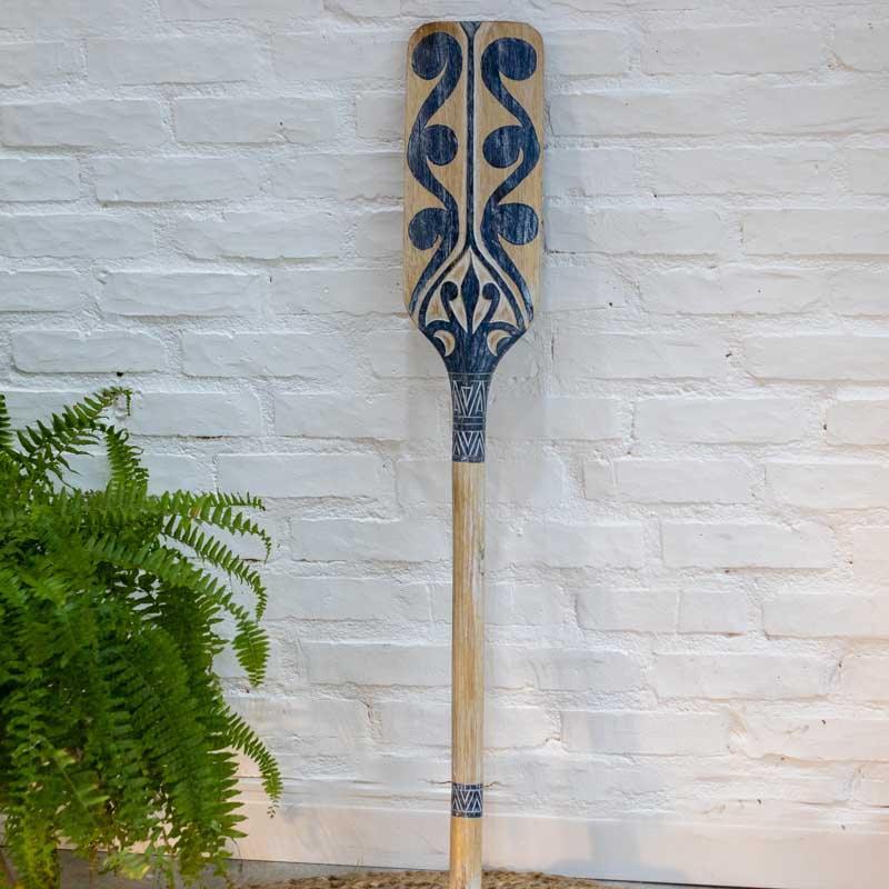 Remo tribal decorativo de Bali em madeira clara com entalhes manuais e pintura artesanal azul.