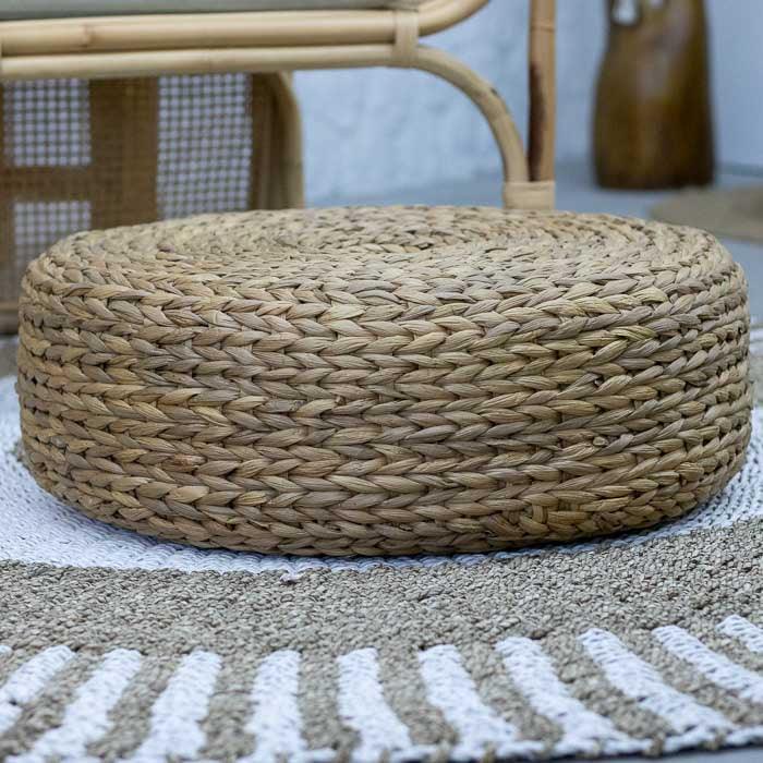 Puff rústico em rattan natural com trançado circular e acabamento fosco ideal para salas tropicais e espaços relaxantes.