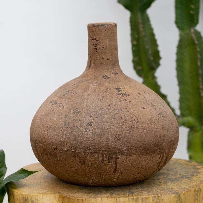 Vaso artesanal Nusa em terracota de Bali com gargalo estreito e corpo bojudo, apresentando textura terrosa e marcas de patina escura.