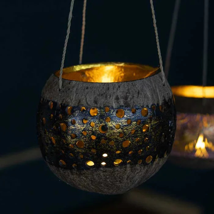 Lanterna de coco com recortes delicados, criando efeitos de luz únicos quando acesa.