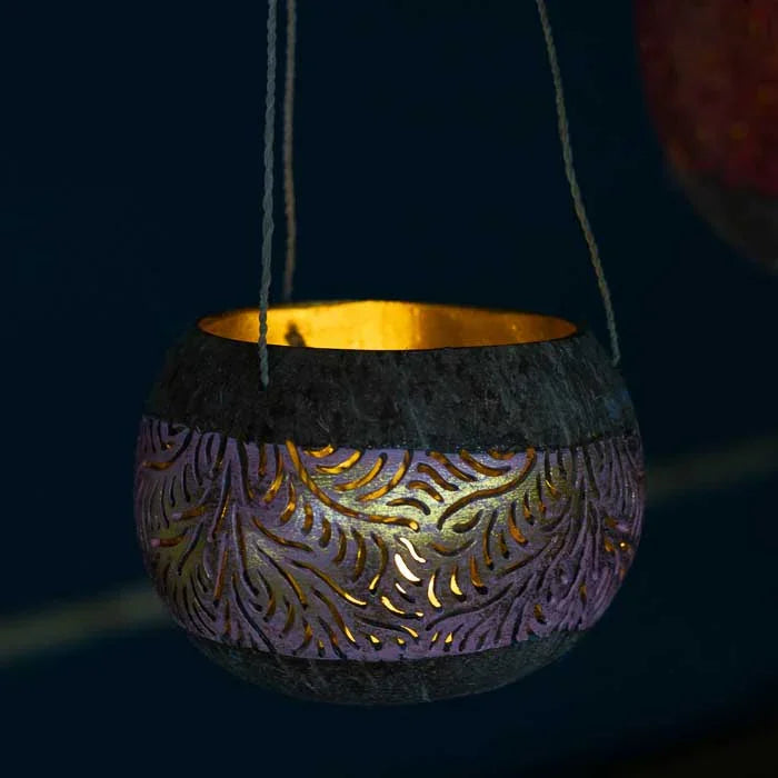 Lanterna artesanal em coco natural com perfurações que formam desenhos de luz.
