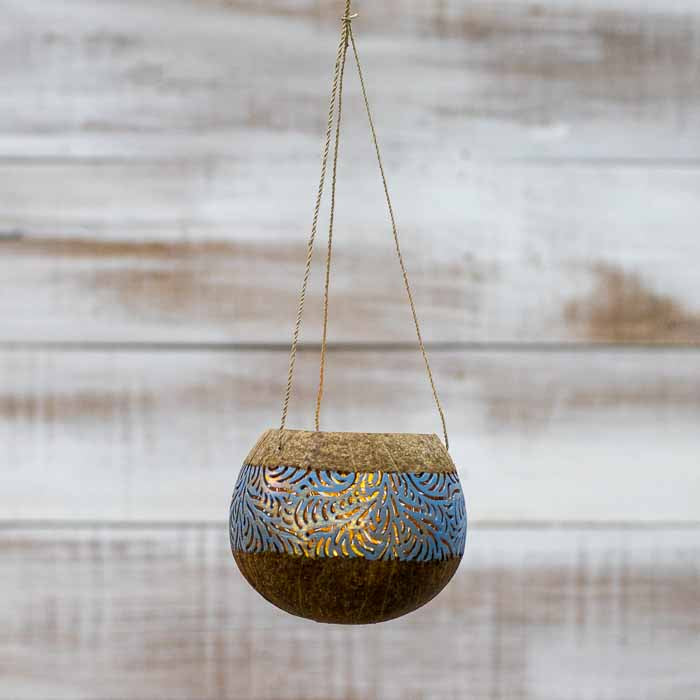 Porta-vela pêndulo suspenso sobre fundo rústico evidenciando o design orgânico.