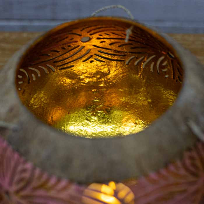 Vista de perfil de porta-vela pêndulo de coco destacando a suspensão por cordas.