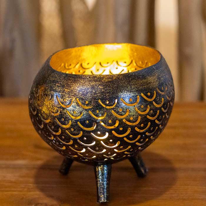 Porta-vela decorativo com recortes feitos à mão em casca de coco.